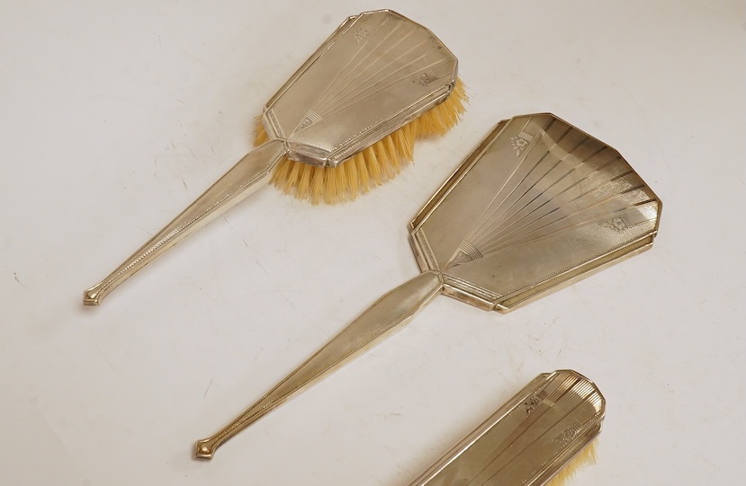 A cased George VI Art Deco silver mounted silver four piece mirror, brush and comb set, Charles S. Green & Co, Birmingham, 1948-1952. Condition - poor to fair to good.